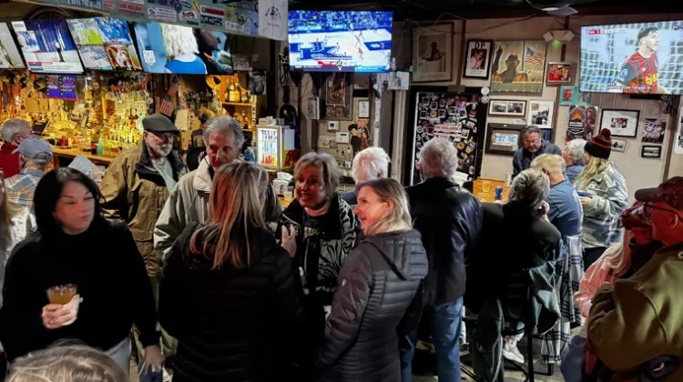 Throng of people with alcohol in their hands celebrating a recently deceased local icon