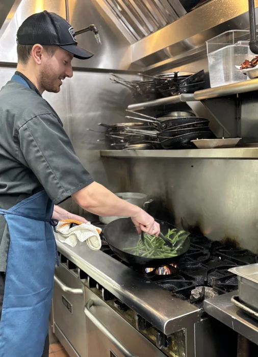 In the kitchen shot of Chef Jacob Mitzel sautéing veggies during the dinner rush at IOPSC's Long Island Cafe.