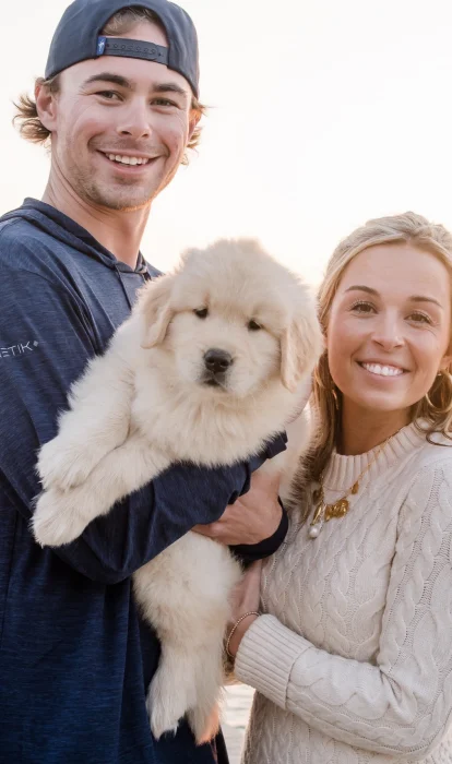 Photo of Baker, IOP's latest Golden Retriever puppy resident, and a young couple that are his owners.