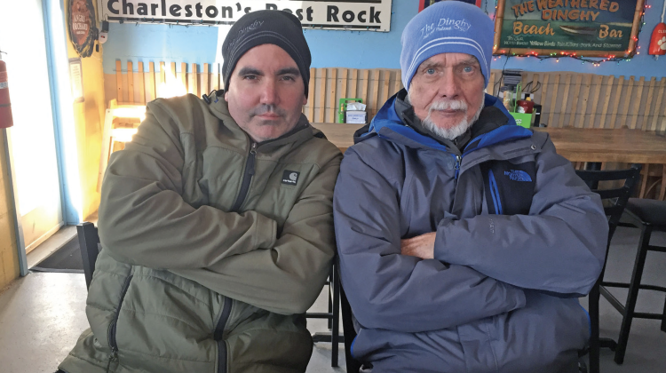 Middle-aged guy sitting cross armed next to an senior male in the same pose