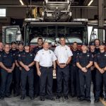 A picture looking into the Isle of Palms fire-station showcasing the IOP Firefighters lined up for a group photo in front of one of their firetrucks.