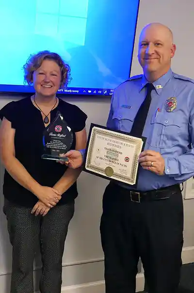 Retiring IOPFD Fire Chief Travis Stafford holding awards with wife Kelly by his side.